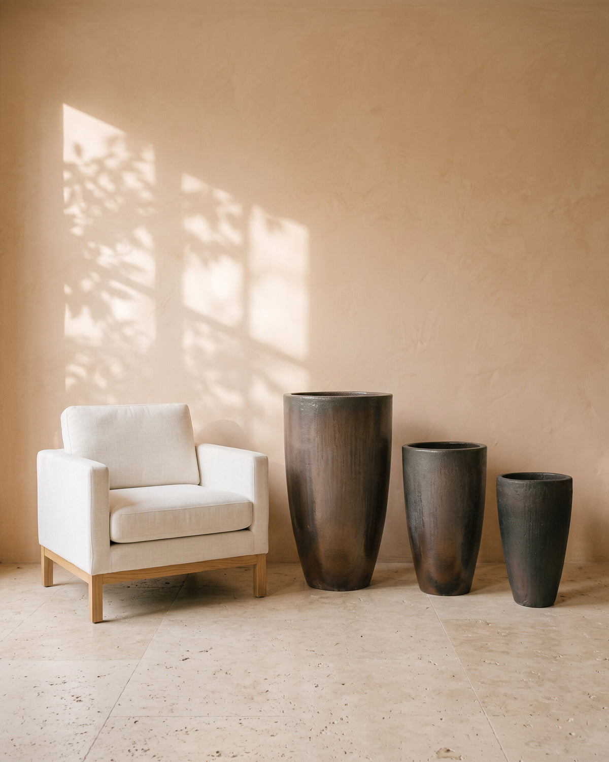 Metallic Charcoal Elongated Pot, all sizes, shown beside a linen armchair for scale