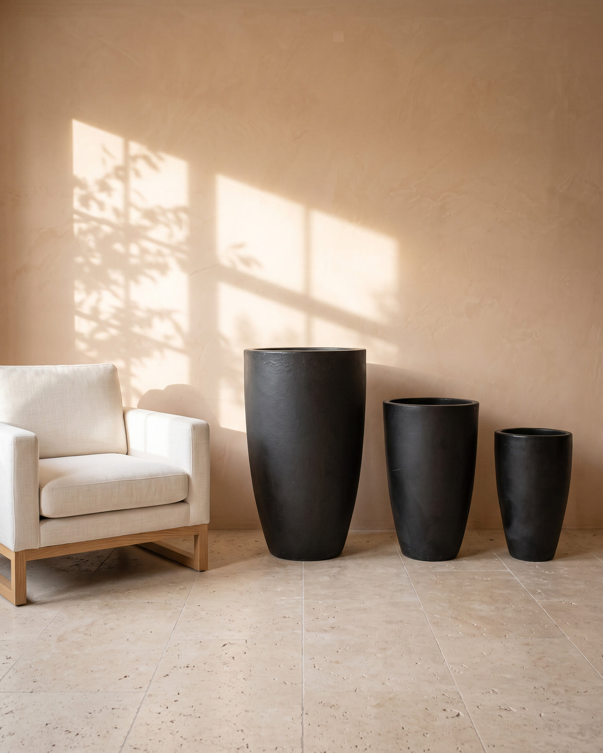 Black Night Tall Glossy Pot, all sizes, shown beside a linen armchair for scale