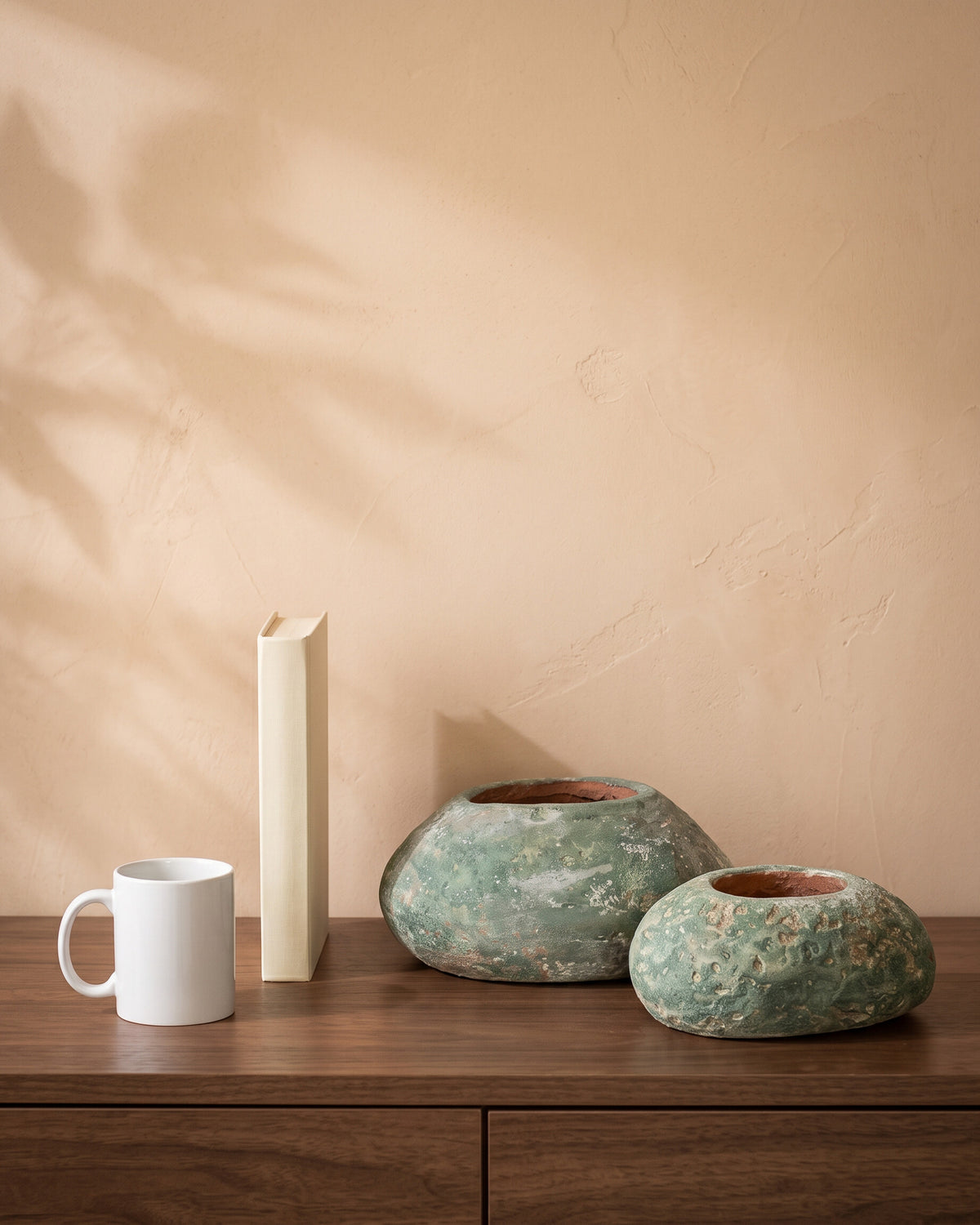 Oval Stone, all sizes, shown on a walnut sideboard next to a coffee mug and a book for scale