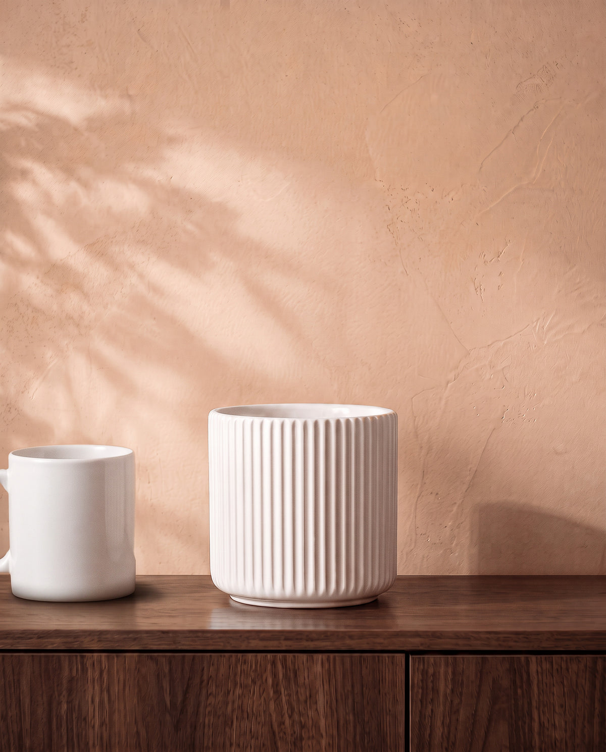 Linear Pot in matte white, on a walnut sideboard beside a coffee mug for scale