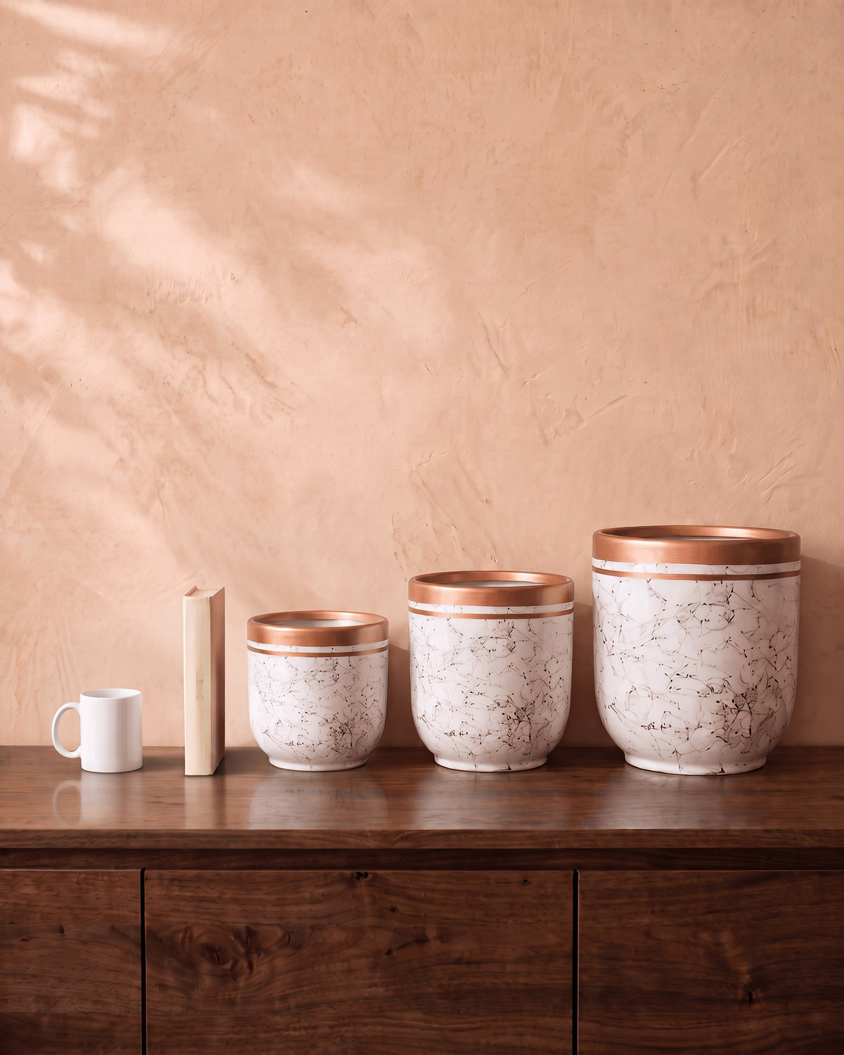 Marble Pot in white, all sizes, shown on a walnut sideboard next to a coffee mug and a book for scale
