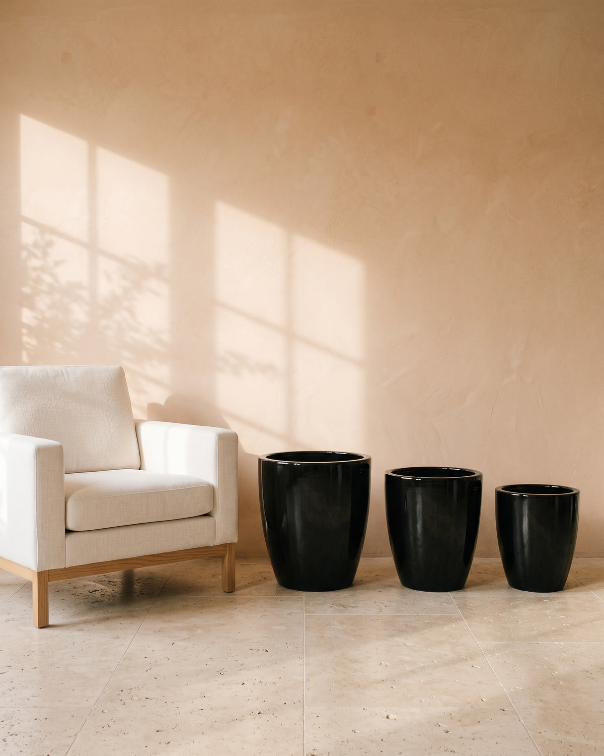 Fine Black Glossy Pot, all sizes, shown beside a linen armchair for scale