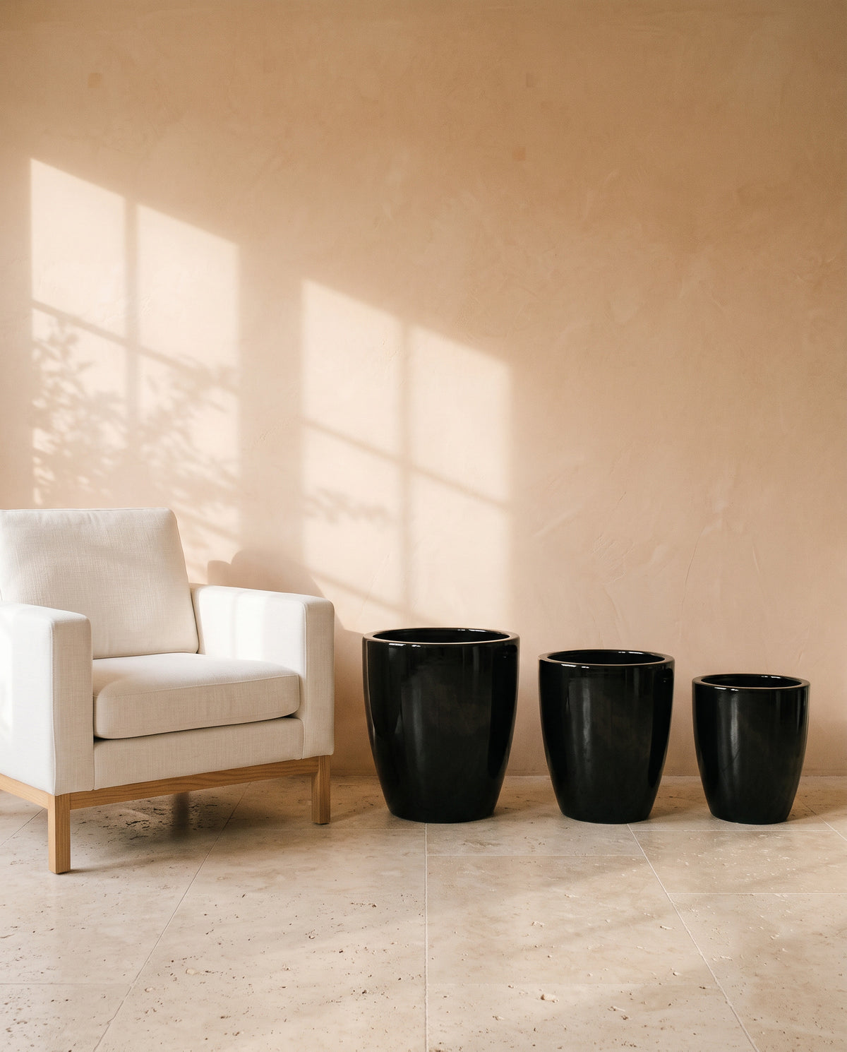Fine Black Glossy Pot, all sizes, shown beside a linen armchair for scale