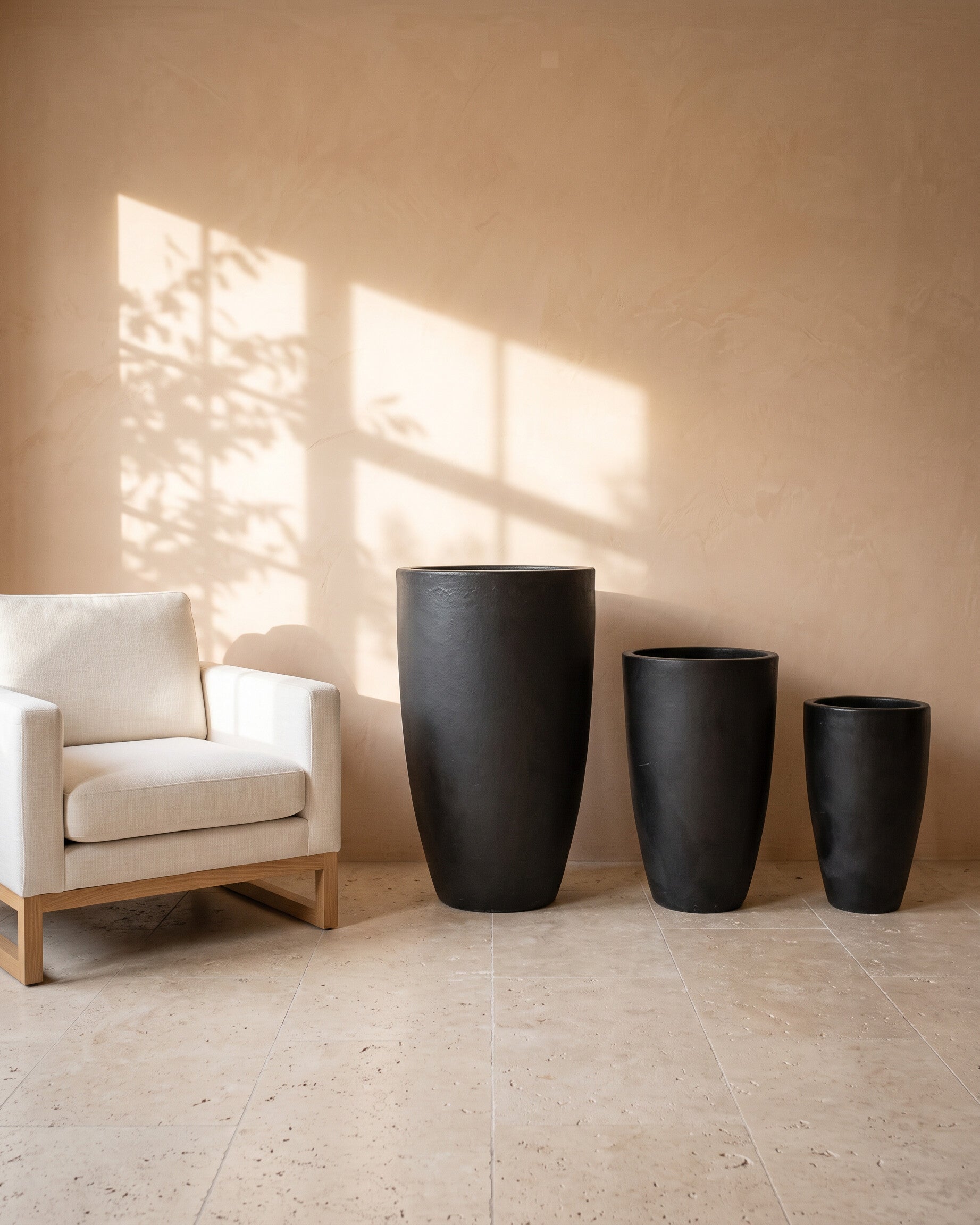Black Night Tall Glossy Pot, all sizes, shown beside a linen armchair for scale