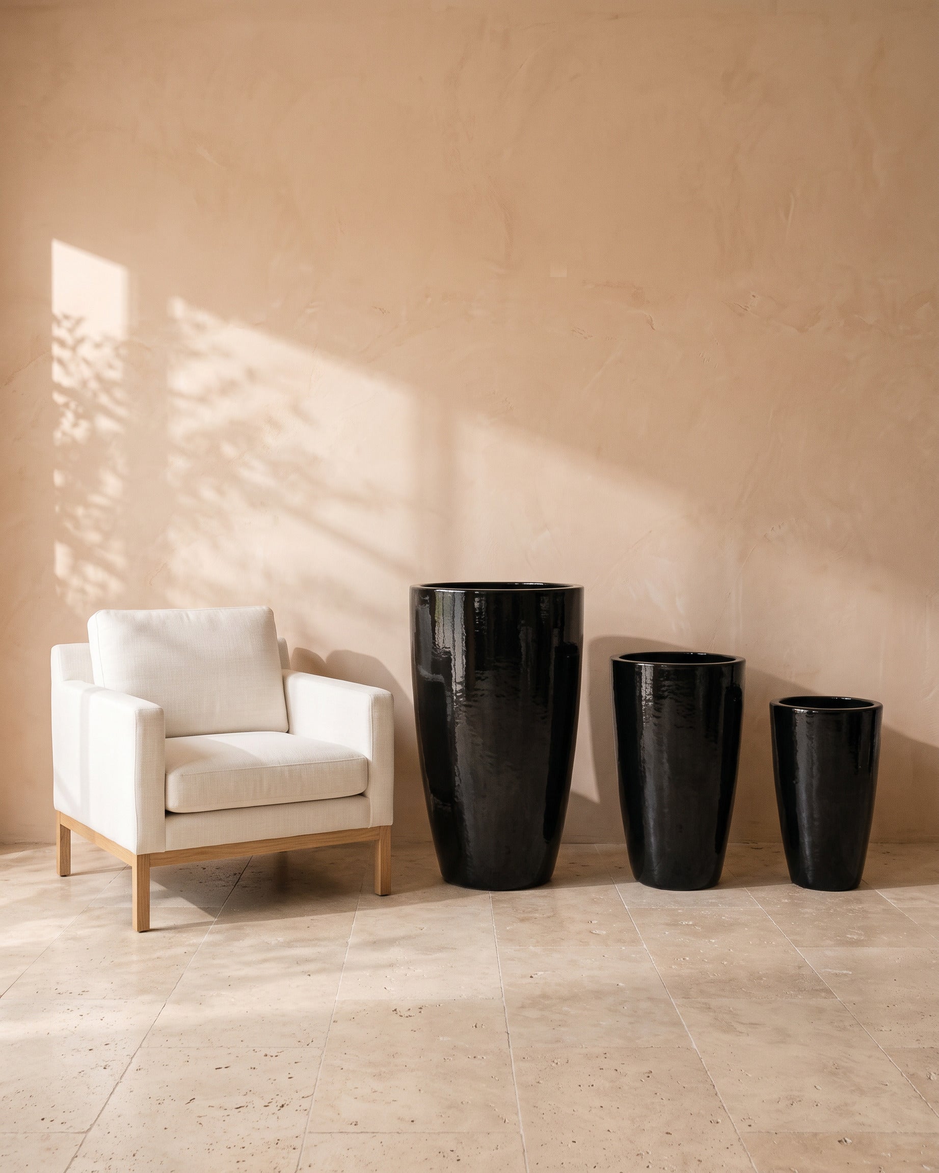 Black Night Tall Glossy Pot, all sizes, shown beside a linen armchair for scale