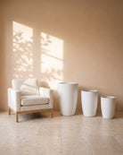 Snow White Glossy Pot, all sizes, shown beside a linen armchair for scale