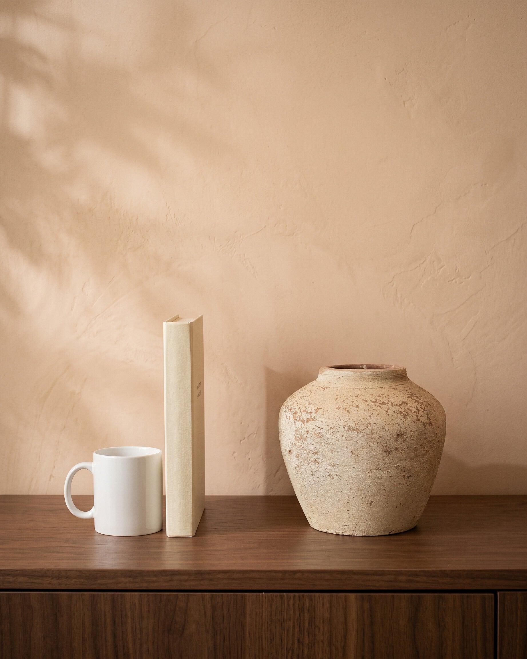 Atlantic Rock Vase, shown on a walnut sideboard next to a coffee mug and a book for scale