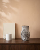 Amber Stone Vase, shown on a walnut sideboard next to a coffee mug and a book for scale