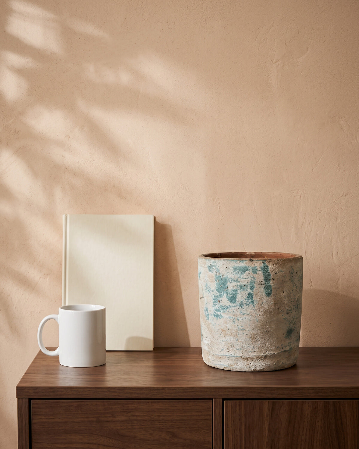 Handcrafted Round Pot, shown on a walnut sideboard next to a coffee mug and a book for scale