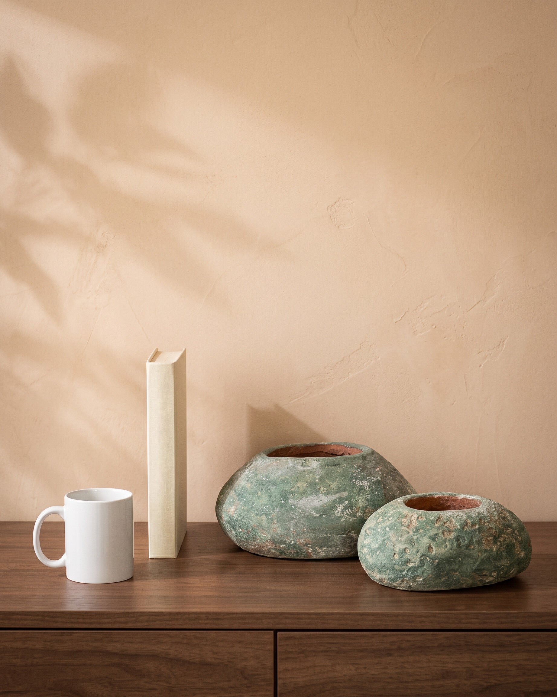 Oval Stone, all sizes, shown on a walnut sideboard next to a coffee mug and a book for scale