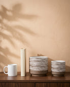 Latte Ribbed Pot, all sizes, shown on a walnut sideboard next to a coffee mug and a book for scale