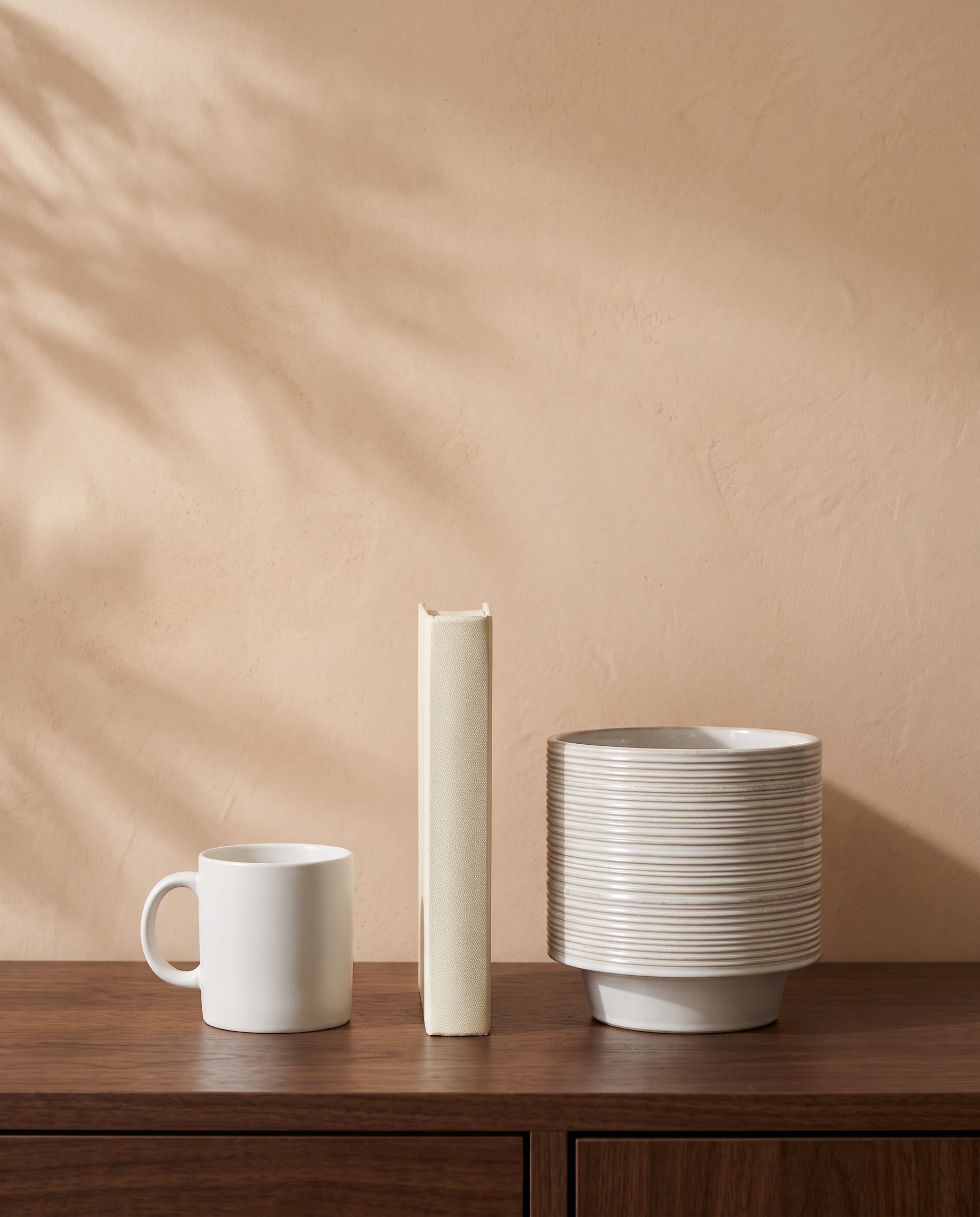 White Groove Pot, shown on a walnut sideboard next to a coffee mug and a book for scale