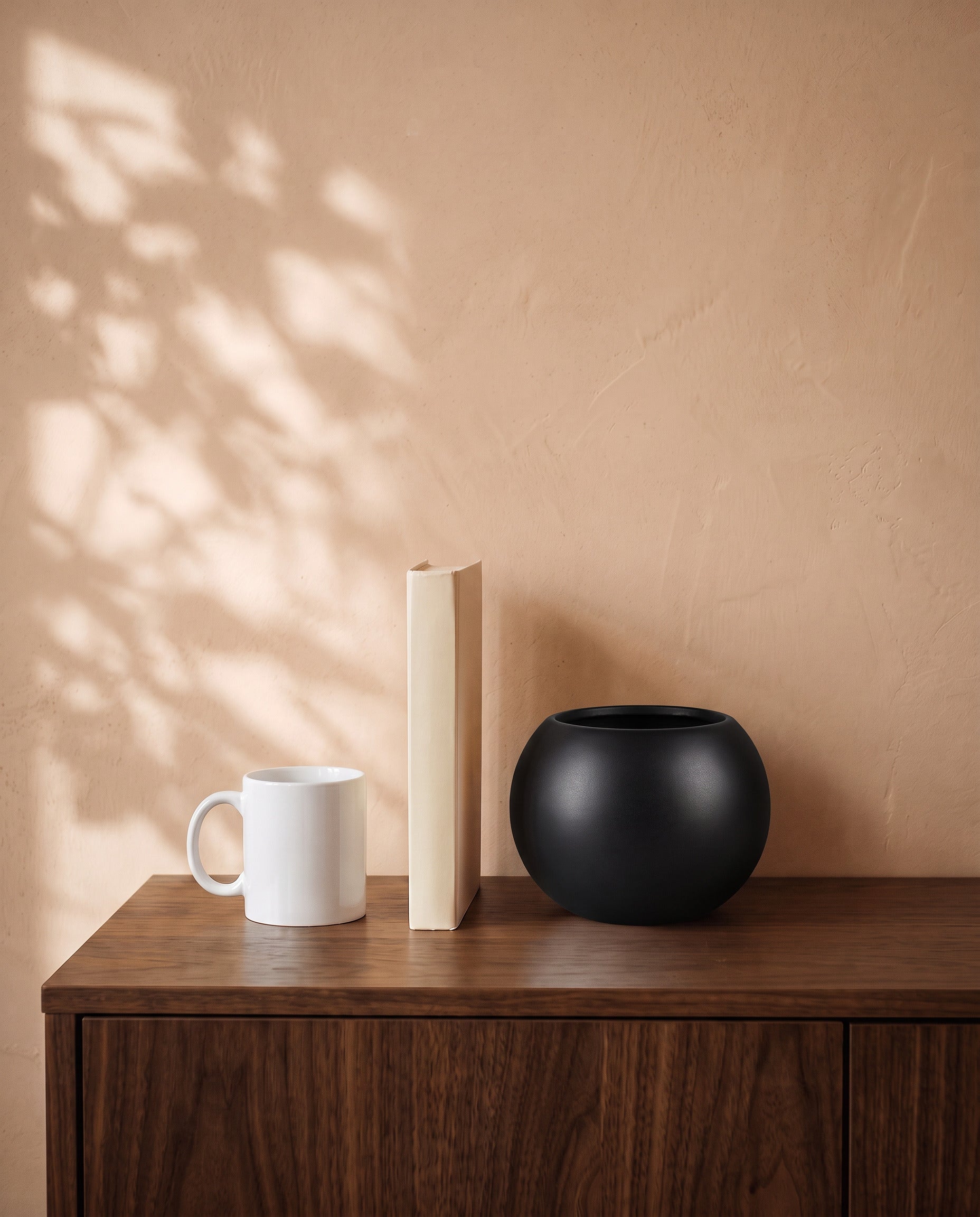 Matt Black Globe, shown on a walnut sideboard next to a coffee mug and a book for scale