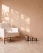 Violet Marble Pot, all sizes, shown on a travertine floor beside a linen armchair for scale