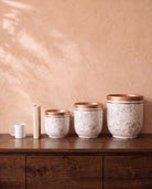 Marble Pot in white, all sizes, shown on a walnut sideboard next to a coffee mug and a book for scale