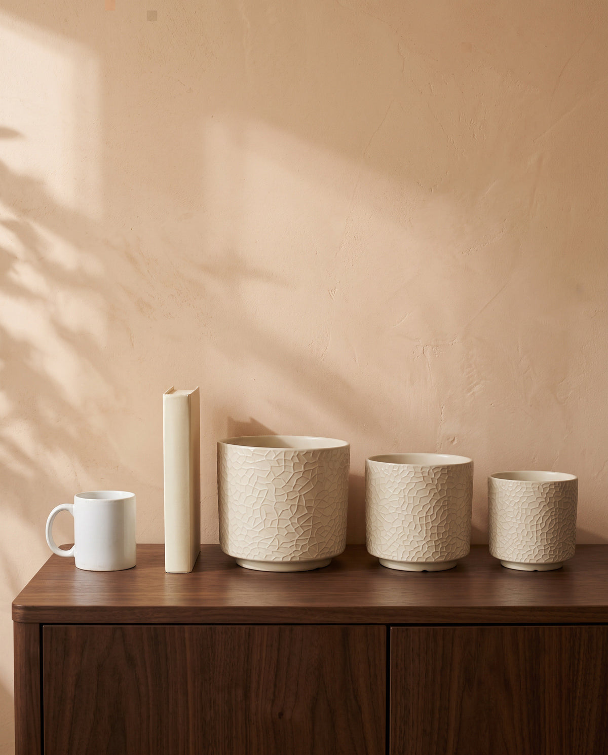 Cracked Ribbed Pot, all sizes, shown on a walnut sideboard next to a coffee mug and a book for scale