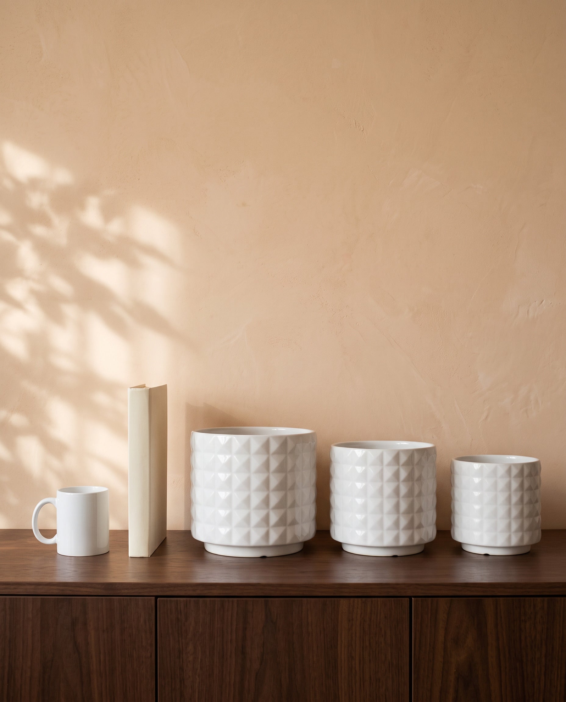 Diamond White Pot, all sizes, shown on a walnut sideboard next to a coffee mug and a book for scale